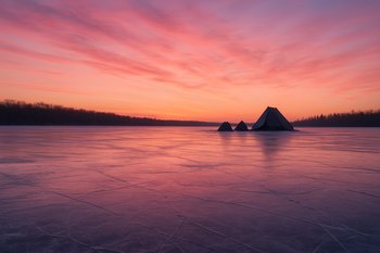 Рассвет над гладким льдом и домиками лагеря на горизонте